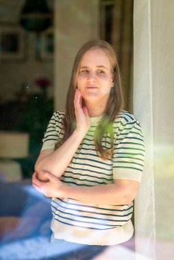 Odadaki pencerenin önünde duran görme engelli bir kadın. Pencereden fotoğraflanmış..