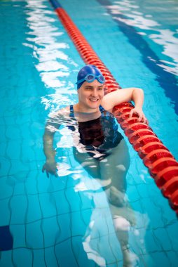 Kapalı havuzda yüzen görme engelli bir kadın. Mayo ve yüzme şapkası takan kendinden emin bir kadın.. 