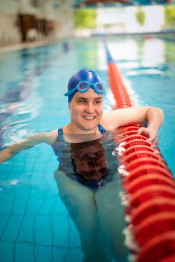 Kapalı havuzda yüzen görme engelli bir kadın. Mayo ve yüzme şapkası takan kendinden emin bir kadın.. 