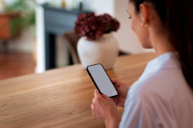Masada oturan ve cep telefonu kullanan bir kadın. Beyaz, boş ekran. Dikiz aynası. Beyaz gömlek giyen kendinden emin bir kadın.. 