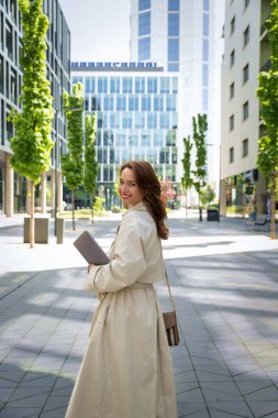 Kendine güvenen bir iş kadını elinde dizüstü bilgisayarla iş bölgesinde dolaşıyor. Orta yaşlı bir profesyonel arkasını dönüp iş kıyafetlerini giyiyor.. 