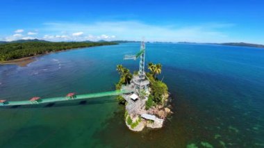Surigao Del Norte, Mindanao 'daki Bacuag Adventure Beach' in hava görüntüleri. İp halatları, zip motorları ve güneşli gökyüzünün altındaki canlı mercan resiflerinin bulunduğu bir adaya uzanan asılı bir köprüyle tropik cenneti keşfedin..