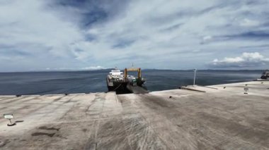 Lipata Limanı, Surigao City 'de deniz lojistiği açık gökyüzü altında sergilenmekte olan yük feribotlarının FPV hava görüntüleri..