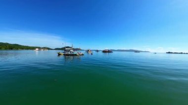 Filipinli uzun menzilli balıkçı teknelerinin placer Rıhtımı, Surigao Del Norte, Kuzey Mindanao 'da mavi gökyüzünün altında demirli hallerini gösteren deniz seviyesindeki engebeli FPV video görüntüleri..