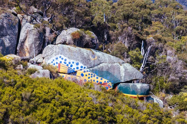 DERBY, AUSTRALIA - SEPTEMBER 23, 2022: Aboriginal fish painting on rock and surrounding landscape in the rural town of Derby on a cold spring morning in Tasmania, Australia