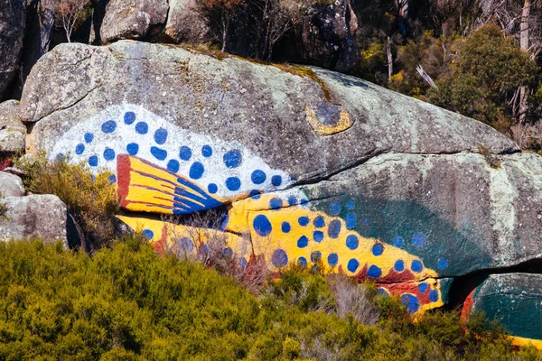 DERBY, AUSTRALIA - SEPTEMBER 23, 2022: Aboriginal fish painting on rock and surrounding landscape in the rural town of Derby on a cold spring morning in Tasmania, Australia