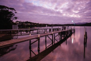 Narooma, NSW, Avustralya 'da gün batımında Wagonga körfezi boyunca uzanan huzurlu bir batış.