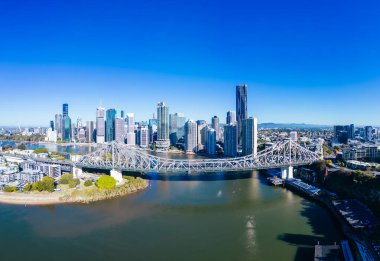 Avustralya, Queensland 'da güneşli bir kış sabahı, New Farm ve Wilson Outlook Reserve banliyölerinden Brisbane ufuk çizgisine ve Story Bridge' e yüksek irtifa manzarası.