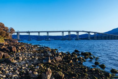 Günbatımında ikonik Tasman Köprüsü açık bir bahar akşamı Hobart, Tazmanya, Avustralya 'daki Derwent Nehri' ni geçer. Clarence 'ın kıyılarından çekildi.