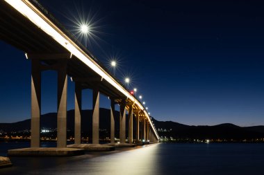 Günbatımında ikonik Tasman Köprüsü açık bir bahar akşamı Hobart, Tazmanya, Avustralya 'daki Derwent Nehri' ni geçer. Clarence 'ın kıyılarından çekildi.