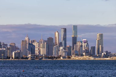 Melbourne silueti Hobsons Körfezi boyunca Williamstown rıhtımındaki Ferguson St Pier 'den kışın Victoria, Avustralya' da alacakaranlıkta yükseliyor.