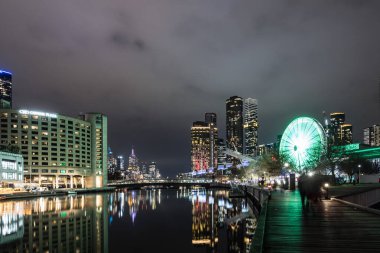 MELBOURNE, AUSTRALIA - 5 Temmuz 2024: Polly Woodside Park ve dönme dolap ve Melbourne silueti Melbourne Sergi Merkezi 'nden alacakaranlıkta görüldüğü gibi