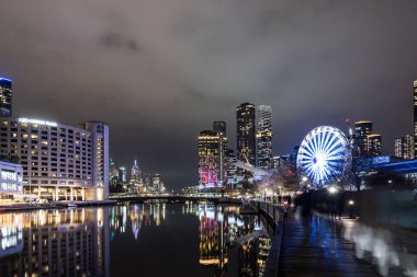 MELBOURNE, AUSTRALIA - 5 Temmuz 2024: Polly Woodside Park ve dönme dolap ve Melbourne silueti Melbourne Sergi Merkezi 'nden alacakaranlıkta görüldüğü gibi