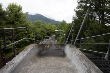 IIZUNA, JAPAN - SEPTEMBER 19, 2024: Start gantry at the now abandoned Nagano 1998 Olympic Spiral luge bobsleigh course on a wet autumn day in Iizuna village, near Nagano, Japan clipart