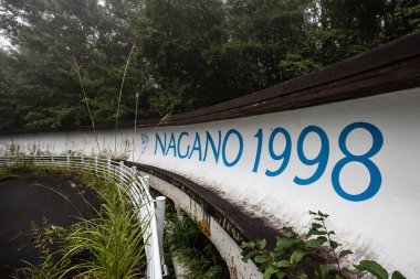 IIZUNA, JAPONYA - 19 Eylül 2024 Japonya 'nın Nagano yakınlarındaki Iizuna köyünde ıslak bir sonbahar gününde terk edilmiş Nagano 1998 Olimpik Spiral kızak pisti