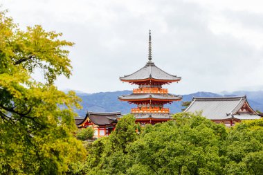 Kyoto, Japonya'da güneşli bir bahar gününde ikonik Kiyomizu-dera tapınağı ve dağ manzarası