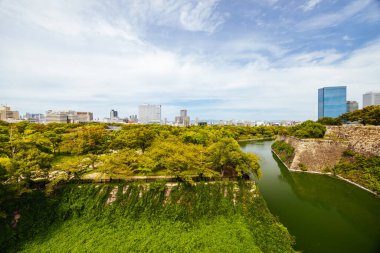 OSAKA, JAPONYA - 25 Eylül 2024 'te Japonya' nın Osaka kentinde sıcak bir sonbahar gününde ikonik Osaka Kalesi ve çevresindeki hendek ve bahçeler