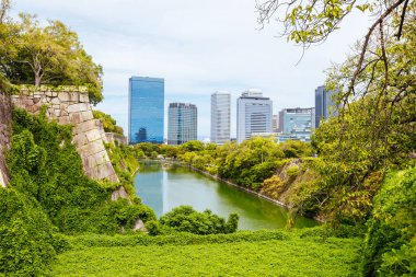 OSAKA, JAPONYA - 25 Eylül 2024 'te Japonya' nın Osaka kentinde sıcak bir sonbahar gününde ikonik Osaka Kalesi ve çevresindeki hendek ve bahçeler