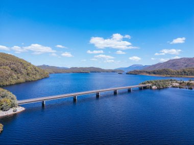 The Bradshaw Bridge across Lake Burbury and surrounding mountain landscape on a warm summers aftenoon near Queenstown in Tasmania, Australia clipart