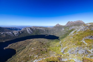 Cradle Mountain, Tazmanya, Avustralya 'da sıcak bir sonbahar sabahında Dove Gölü' nden Hansons Tepesi ve Cradle Dağı 'na doğru dağ manzarası.