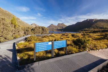 Cradle Mountain, Tazmanya, Avustralya 'da günbatımına yakın ılık bir sonbahar öğleden sonrasında Dove Gölü ve Cradle Dağı' nın etrafındaki patikalar ve patikalar.