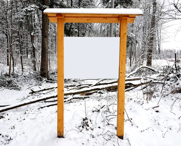 Empty advertisement wooden board in the winter scenery forest.