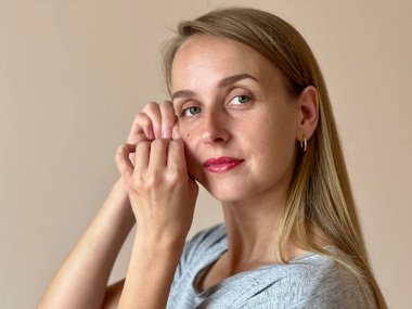 Mutlu, orta yaşlı, çekici bir kadın yüzüne dokunuyor ve yüz masajı yapıyor. Yüksek kalite fotoğraf