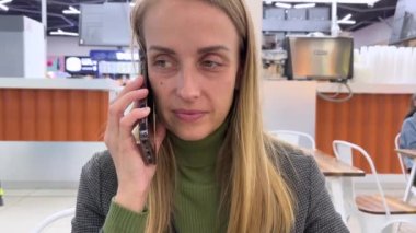 Halka açık bir yerde telefonla konuşmak. Gıda mahkemesinde arkadaşıyla konuşan genç bir kadın. Yüksek kalite 4k görüntü