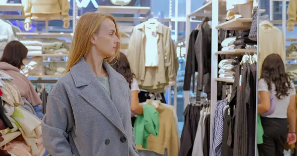 Lady tries on a trendy modern coat of a clothing boutique store in the Mall. The customer chooses a coat in the shop. High quality photo