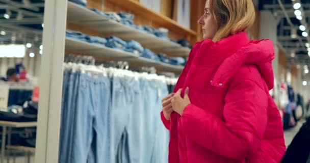 Wanita Muda Berbaju Putih Mencoba Mengenakan Mantel Merah Dengan Butik — Stok Video