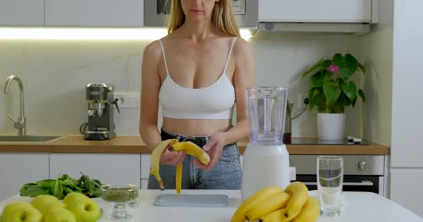 女性はボード上のバナナをカットし それをブレンダーにします 健康的なスムージーのコンセプトを準備します 高品質の4K映像 — ストック動画