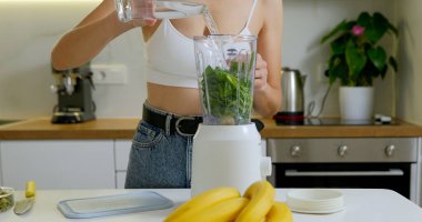 Kadın blender 'a su doldurup tohum koyuyor. Sağlıklı meyve püresi konsepti hazırlanıyor. Yüksek kalite fotoğraf