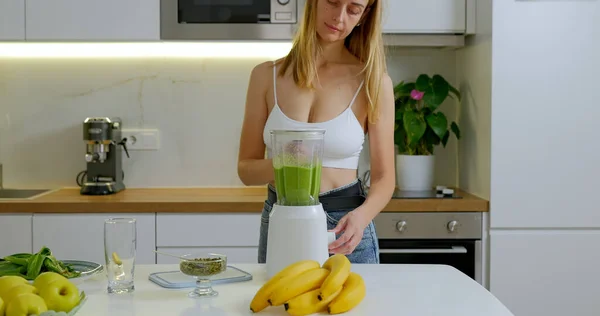 Woman is making green spinach and banana smoothie in blender. High quality photo