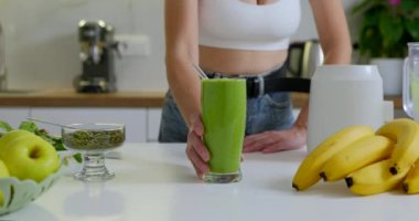 Bir bardak yeşil vejetaryen smoothie ile sportif bir kadın. Kız bir bardak meyve püresi taşıyor. Yüksek kalite 4k görüntü