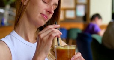 Kadınlar arka planı bulanık, samanlı buzlu kahveyi sever. Yüksek kalite 4k görüntü