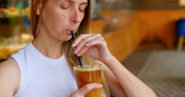 Kadın modern bir kafede dinlenirken buzlu kahveyi pipetle karıştırıyor. Yüksek kalite fotoğraf