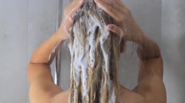 Duşta şampuan köpüğüyle saç yıkayan bir kadın. Yüksek kalite 4k görüntü