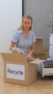 Evde geri dönüşüm için kıyafet sıralayan bir kadın. Yüksek kalite dikey 4k görüntü