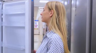 Hırdavatçıda buzdolabının kapısını inceleyen kadın. Yüksek kalite 4k görüntü