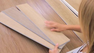 Hırdavatçıdan ahşap kaplama döşeme panelleri seçen bir kadın. Dokuları ve gölgeleri karşılaştırıyor, yenileme, iç tasarım ve modern ev geliştirme projeleri için mükemmel..