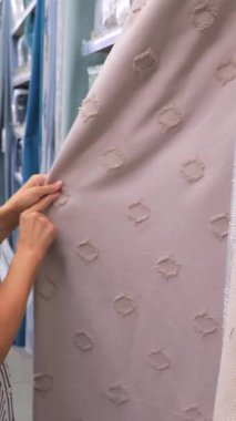 Kadın kumaş perdesini ev eşyaları mağazasında inceliyor, kumaşı ve dokuyu hissediyor. İç alışveriş kavramı, ev tekstili ve modern mobilyalar şık ve rahat ev tasarımı..