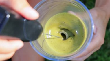 Plastik bardakta el yapımı köpükle karıştırılmış buzlu kibrit sütlü lattenin yakın çekim görüntüsü. Kremalı yeşil çay içeceği, yaz hidrasyonu, antioksidan ve sağlıklı bir yaşam tarzı için mükemmel..