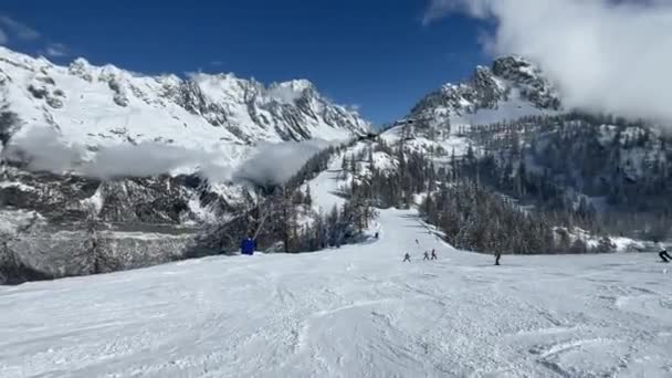 スノーボーダーやスキーヤーのPovは バックグラウンドで晴れたモンブランと他のスキーヤーが住んでいるよく打ち負かされた斜面を降りる 経験豊富なプロのスノーボーダーのアクティブな映像 — ストック動画