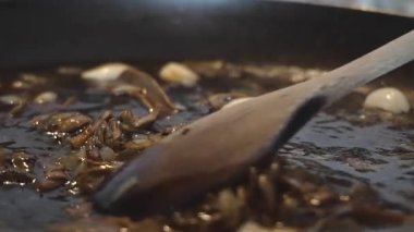 Tahta bir kaşık porcini mantar sosunu karıştırarak zengin Akdeniz malzemelerini harmanlıyor. Makroyu 45 derecelik açıyla yakın çekim, 4K yavaş çekim (120 fps,% 20 yavaşlatılmış))