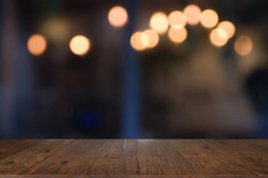 Soyut bulanık kafenin önündeki boş ahşap masa, geceleri restoran. Montaj ürünü görüntüleme veya tasarım için anahtar görsel düzeni - Resim