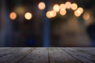 Soyut bulanık kafenin önündeki boş ahşap masa, geceleri restoran. Montaj ürünü görüntüleme veya tasarım için anahtar görsel düzeni - Resim
