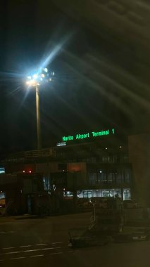 Chiba, Japan - 8 Aug 2024: Narita Airport Terminal 1 banner glowing in green at night.