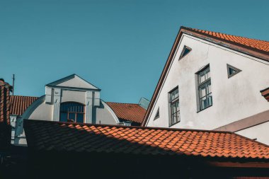 Mavi gökyüzüne karşı kırmızı çatıları olan beyaz evler.