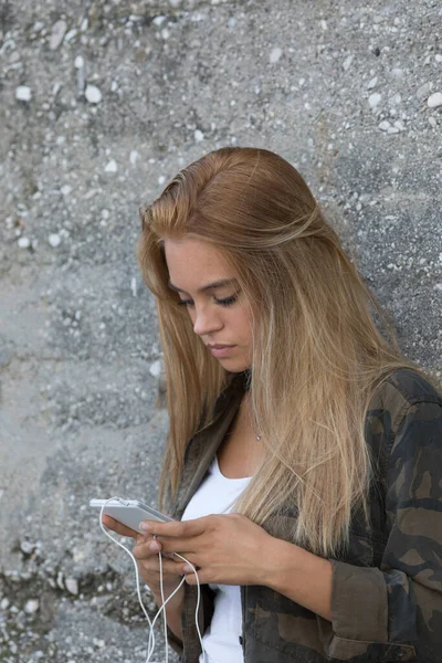 Menina Loira Informal Encostada Parede Concreto Enquanto Usa Seu Smartphone — Fotografia de Stock