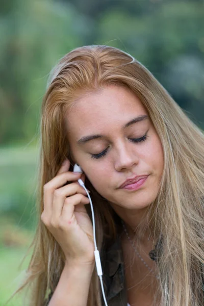 女孩紧闭双眼 戴上智能手机耳机 全神贯注地听音乐 — 图库照片